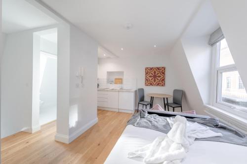 ein weißes Schlafzimmer mit einem Bett und einem Tisch in der Unterkunft HAFH in Paddington - Double studio 3 in London