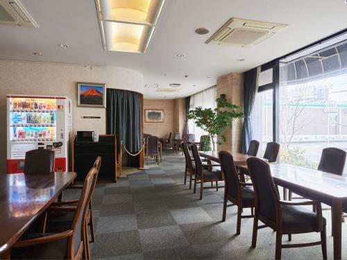 富士的住宿－Tabist Hotel New Central，用餐室配有木桌和椅子