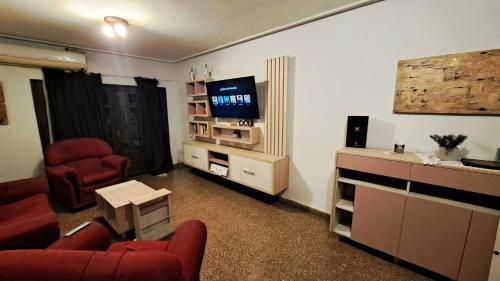 un soggiorno con sedie rosse e TV di Dpto amplio de categoria en Tucumán a San Miguel de Tucumán
