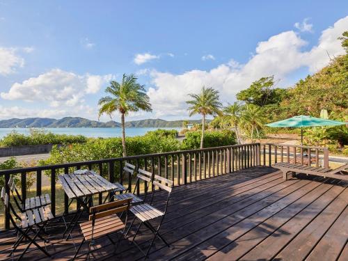 a wooden deck with two chairs and an umbrella at Villa AdanRose Amami in Akagina