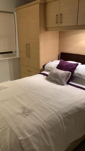 a bedroom with a large white bed with purple pillows at Spar Court One bed apartment in Burton upon Trent