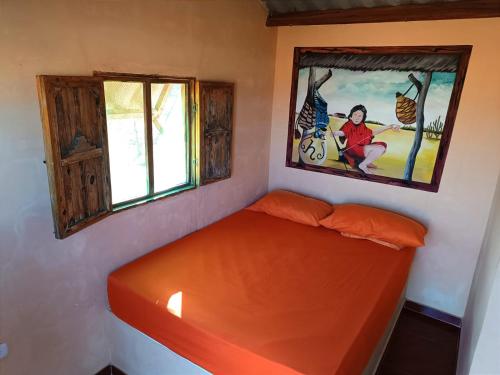 un letto arancione in una stanza con un dipinto sul muro di El Kachi Hospedaje y Restaurante a Uribia