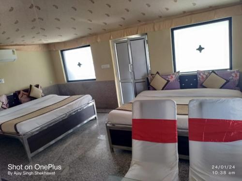 two beds in a room with three windows at Virasat The Tent Villa in Jaipur