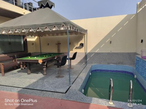 a pool table under a canopy next to a swimming pool at Virasat The Tent Villa in Jaipur