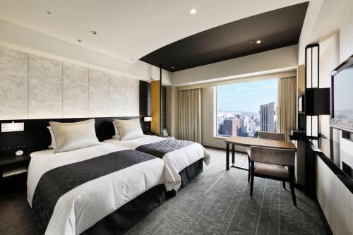 a bedroom with a bed and a desk and a window at Hotel Granvia Kyoto in Kyoto