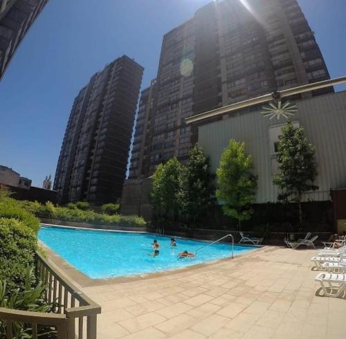 a group of people in a swimming pool with tall buildings at departamentos santiago centro moneda SUAGON APART HOTEL in Santiago
