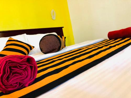 a bed with a black and yellow striped blanket on it at Green Horizon Ella in Ella