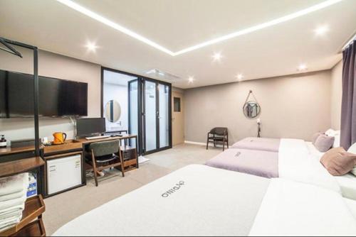 a bedroom with two beds and a desk and a television at Busan Station Dino Hotel in Busan