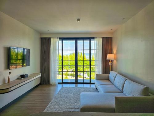 a living room with a couch and a large window at Estella Khao Yai in Khao Yai