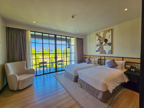 um grande quarto de hotel com duas camas e uma cadeira em Bergh Apton Khao Yai em Khao Yai