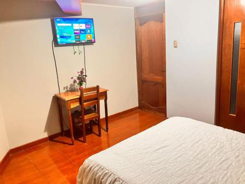 a bedroom with a bed and a desk and a television at Hostal El Rancho in Huancayo