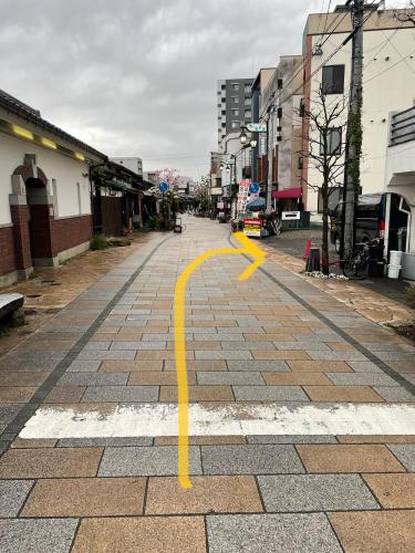 an empty street with a yellow arrow on a road at Nawate Guesthouse in Matsumoto
