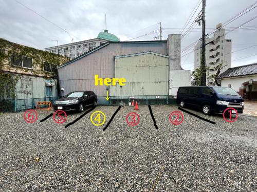 two cars parked in a parking lot in front of a building at Nawate Guesthouse in Matsumoto