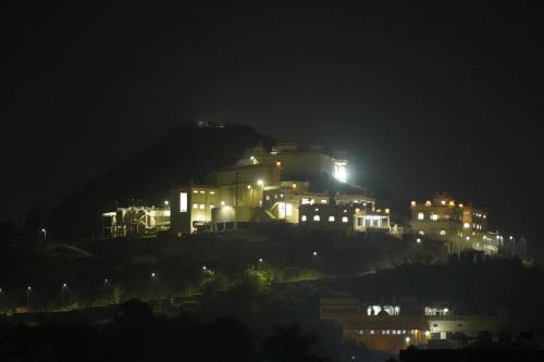 a lit up building on a hill at night at Shri Daulat Villas in Udaipur