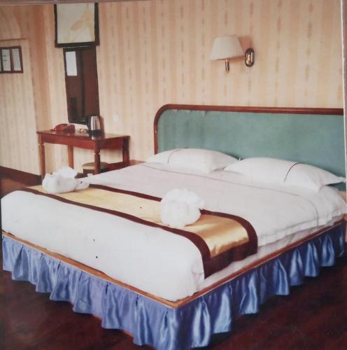 een groot bed met witte kussens in een slaapkamer bij Dansavanh Hotel in Muang Xay