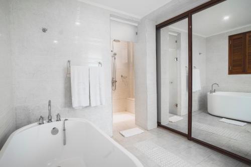 La salle de bains blanche est pourvue d'une baignoire et d'une douche. dans l'établissement Sarova Maiyan Nanyuki, à Nanyuki