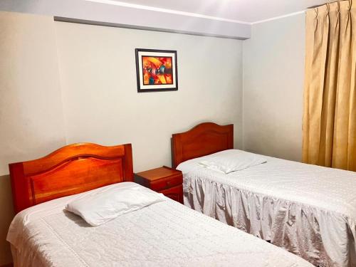 1 dormitorio con 2 camas y una foto en la pared en Hostal El Rancho, en Huancayo