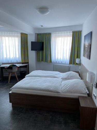 a bedroom with a large bed and a desk at Hotel Meyer in Hildesheim