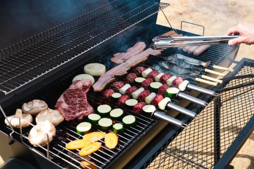 a person cooking meat and vegetables on a grill at 郷音 ～G.O.A.T～ in Tsuru 