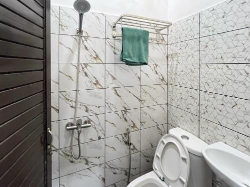 een badkamer met een toilet en een groene handdoek bij RedDoorz at Rose House Simpang Pemda Medan Selayan in Sunggal