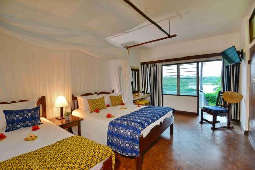 a hotel room with two beds and a window at Mnarani Beach Club in Kilifi
