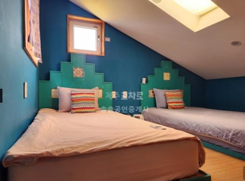 Seonjau in Jeju في جيجو: غرفة نوم بسريرين وجدار ازرق