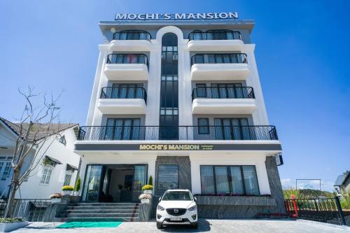 a white building with a small car parked in front of it at Mochi's Mansion in Da Thien