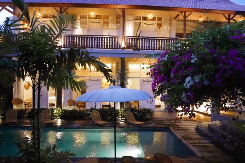 a hotel with a swimming pool and an umbrella at Amar Boutique Hotel in Canggu