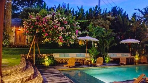 a pool at a resort with chairs and umbrellas at Amar Boutique Hotel in Canggu