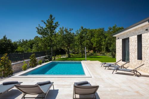 a swimming pool with chaise lounge chairs next to a house at Villa Gala by Rent Istria in Kringa