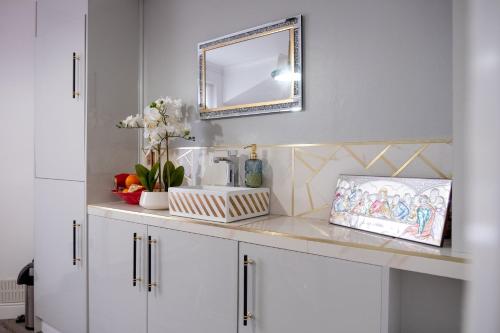 a bathroom with white cabinets and a mirror at Spacious Double Bedroom in Shooters Hill in London