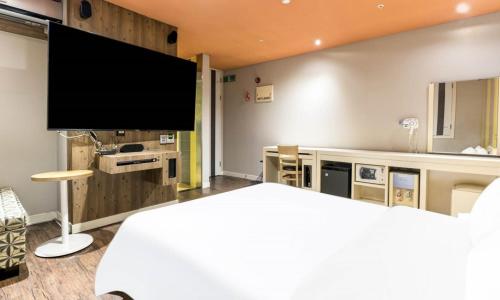 a bedroom with a large flat screen tv on the wall at Dongtan BobosHotel in Hwaseong