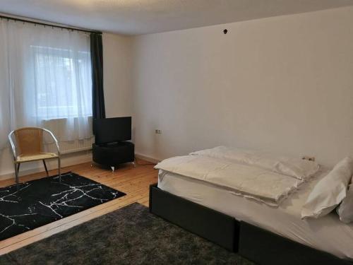 a bedroom with a bed and a chair and a window at delblaiso suite in Memmingen