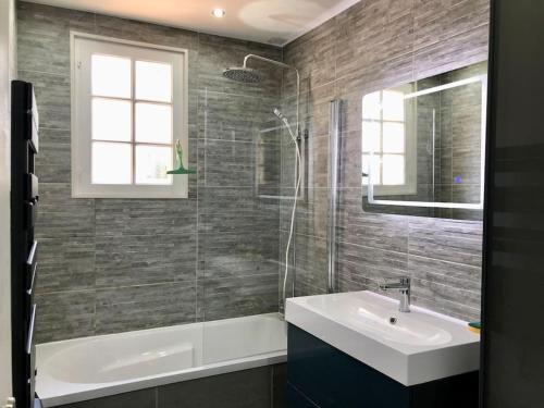 ein Badezimmer mit einem Waschbecken, einer Badewanne und einem Spiegel in der Unterkunft Villa 3* piscine vue montagne proche mer & Espagne in Le Boulou