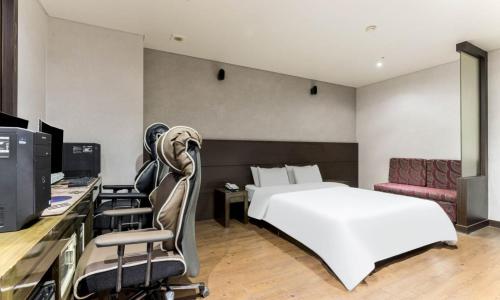 a bedroom with a bed and a desk with a computer at Dongtan BobosHotel in Hwaseong