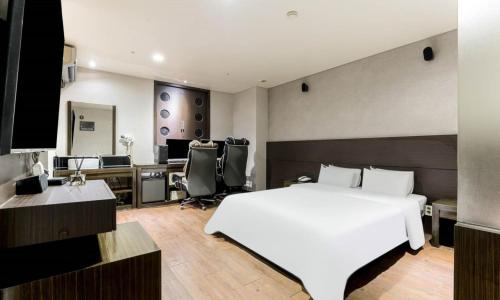 a bedroom with a white bed and a desk at Dongtan BobosHotel in Hwaseong