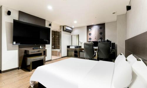 a bedroom with a large white bed and a television at Dongtan BobosHotel in Hwaseong