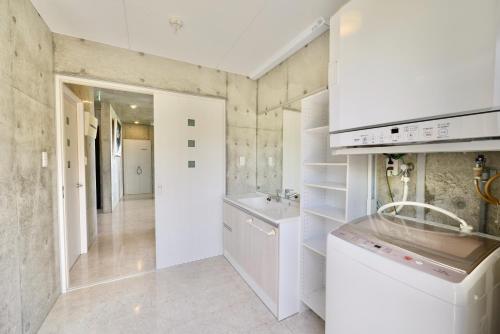 uma cozinha branca com um lavatório e um balcão em Guest House Karst em Ufudo