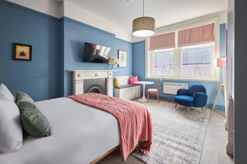 een blauwe slaapkamer met een bed en een open haard bij Arlington House Hotel - Luxurious Self Check-In Ensuite Rooms in the Centre of Wooler in Wooler