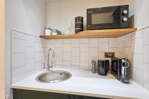 a kitchen counter with a sink and a microwave at Arlington House Hotel - Luxurious Self Check-In Ensuite Rooms in the Centre of Wooler in Wooler