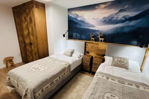 a bedroom with two beds and a painting on the wall at Alpen Lodge Premium Apartment in Mezzana