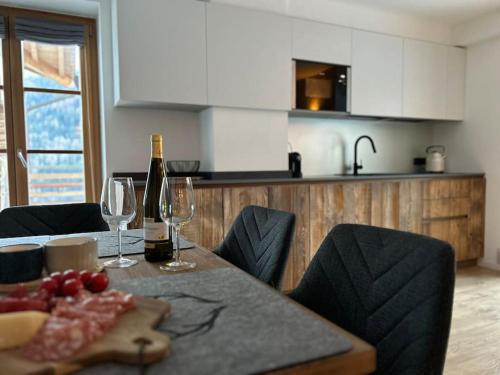 a kitchen with a table with a bottle of wine and wine glasses at Alpen Lodge Premium Apartment in Mezzana