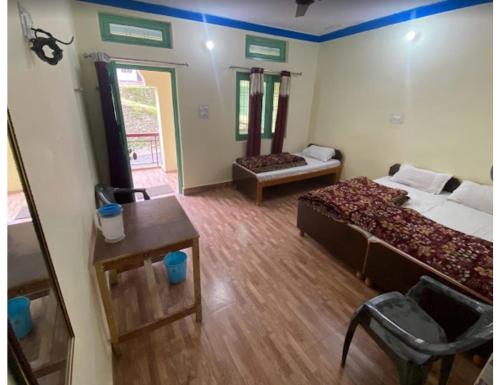 um quarto com duas camas e uma mesa em Anoop Tourist Guest House, Phata em Phata