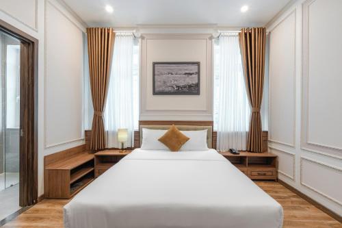 a bedroom with a large white bed and windows at PINE VIEW Hotel Dalat in Da Lat