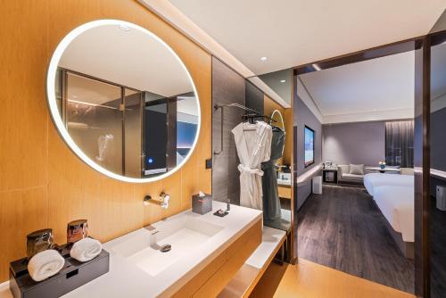 a bathroom with a sink and a mirror and a tub at Intercity Yangzhou Slender West Lake in Yangzhou