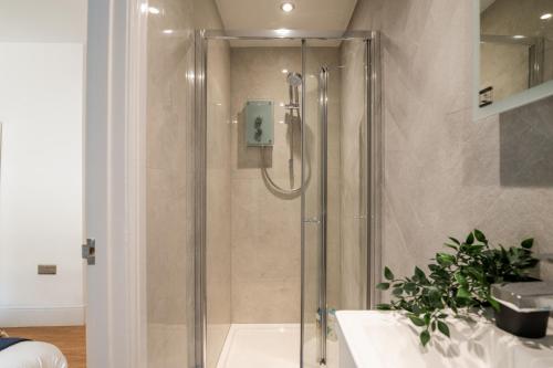 a shower with a glass door in a bathroom at LiveStay - Modern Apartments on Acton Lane in London