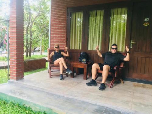 two men sitting in chairs on a porch at Sigiriya Cashew Palace Resort in Sigiriya