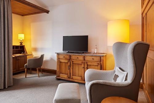 a living room with a television and two chairs at Parkhotel Oberstaufen in Oberstaufen