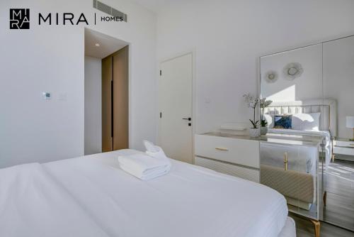 biała sypialnia z białym łóżkiem i lustrem w obiekcie Mira Holiday Homes - Lovely 1 bedroom in Midtown w Dubaju