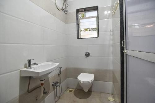 La salle de bains blanche est pourvue d'un lavabo et de toilettes. dans l'établissement EMPYREAN STAY ll 2BHK ll PRIVATE POOL ll GOOD LUCK VILLA ll FREE BREAKFAST, à Lonavala